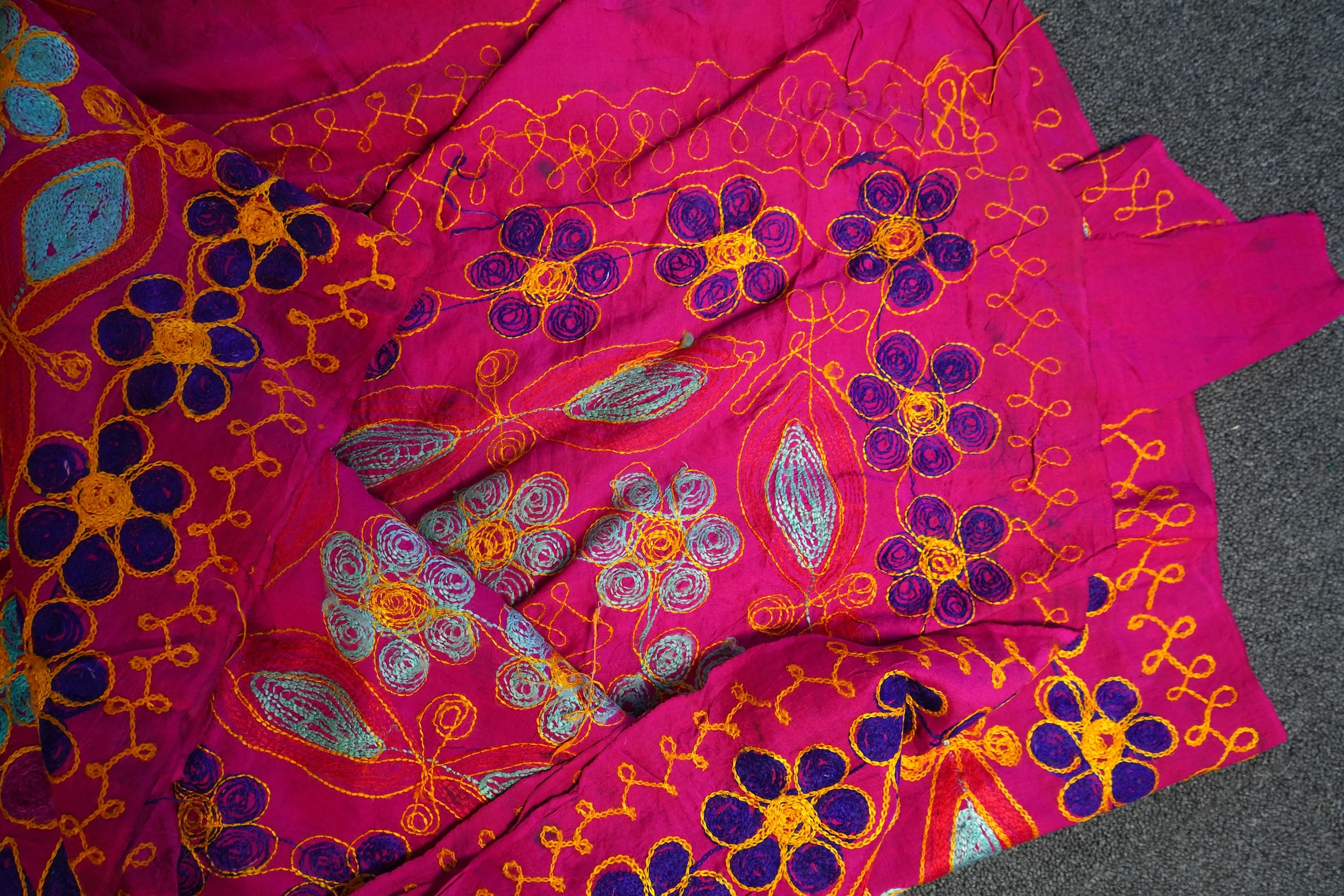 A large Indian silk embroidered and mirrored temple pelmet, with a cerise silk embroidered hanging and a length of cotton wax resist style printed fabric. Temple pelmet 468cm long x 70cm, deep. Condition - the pelmet has